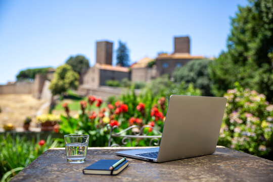 Laptop and notebook on outdoor desk for remote work in garden setting