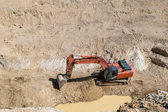 Escavadora hidr&aacute;ulica de lagartas a operar num terreno arenoso e h&uacute;mido durante trabalhos de escava&ccedil;&atilde;o e movimenta&ccedil;&atilde;o de terras num estaleiro de constru&ccedil;&atilde;o civil