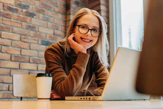 Smiling woman with glasses working on laptop in modern office