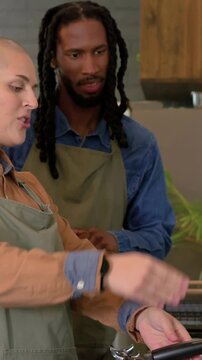 Vertical video: Using portafilter, aproned barista training tamping at coffee counter, copy space