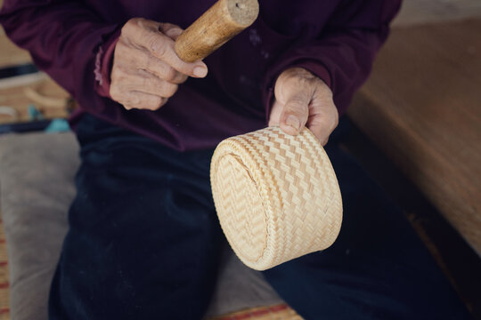 Artisan hands making traditional bamboo sticky rice container or Kratip Khao using wickerwork technique.
