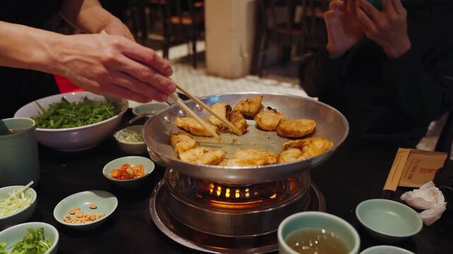 Chefs prepare traditional cha ca fish with turmeric and fresh herbs at Cha Ca Thang Long restaurant in Hanoi, Vietnam, showcasing a classic northern Vietnamese culinary experience.