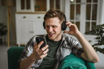 Fototapeta premium Young man enjoying music listening to headphones at home