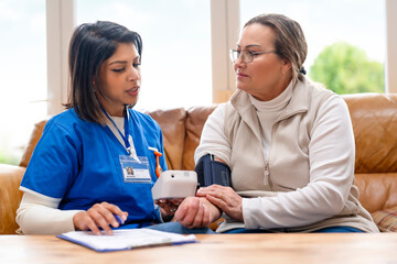 Fototapeta premium Nurse checks blood pressure of patient in a bright living room during daytime