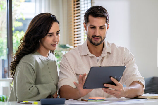 Couple reviewing personal financial calculate tax document while checking expense and payment at home, inspecting bills, budget, insurance, savings, and receipts