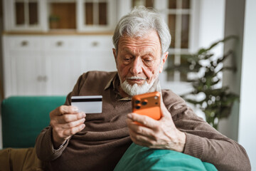 Senior man making online purchase with credit card and smart phone