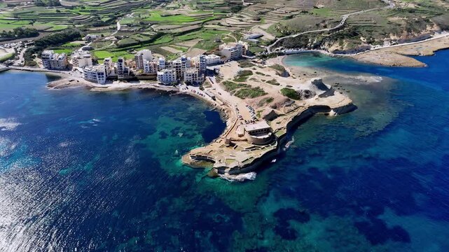 Scenic Aerial View of Gozo Island Malta Featuring Marsalforn Bay Coastline and Qolla l-Bajda Battery During a Sunny Summer Day with Turquoise Mediterranean Sea and Verdant Terraced Fields Landscape