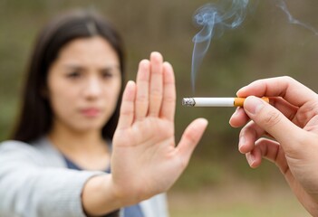 Obraz premium A woman refusing a lit cigarette with stop gesture, anti smoking concept.