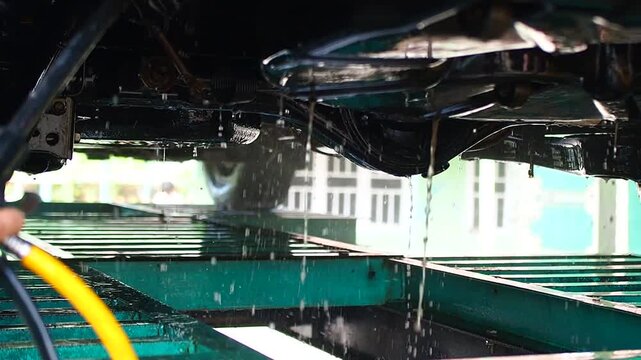 Car Underbody Cleaning with High-Pressure Water Spray on a Vehicle Lift