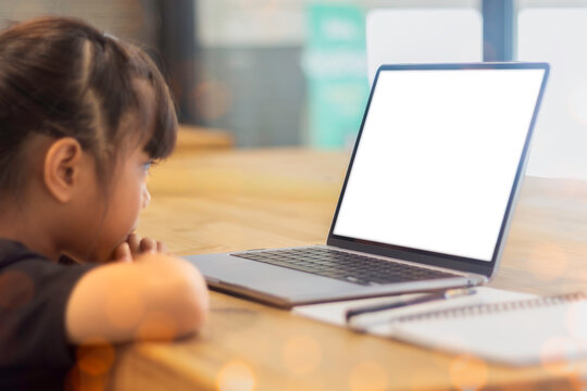 Child watching a blank laptop screen while studying at home, concept of online education, remote learning, and digital classroom with empty display for content placement.