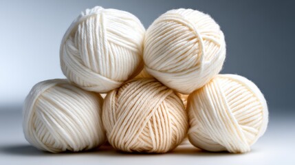 A beautifully arranged stack of soft wool yarn balls in cream tones, highlighting texture and warmth, ideally suited for knitting or crafting projects.