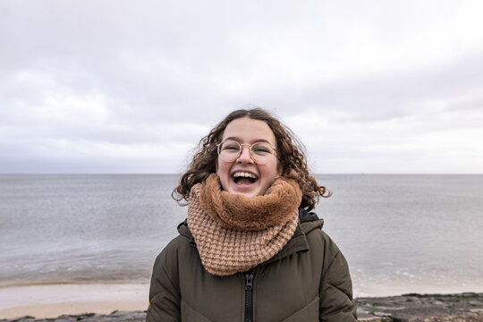Smiling girl enjoying winter by the sea in an authentic outdoor portrait