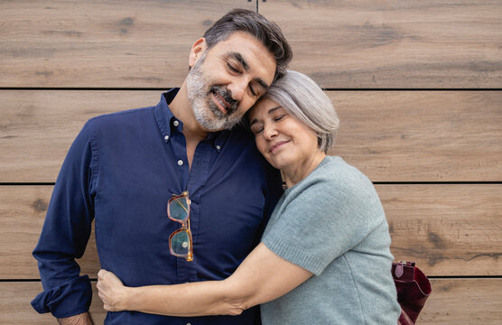 Happy couple embracing in front of a wooden background outdoors