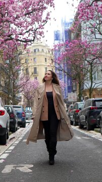 Stylish young woman walking on a parisian street with cherry blossom