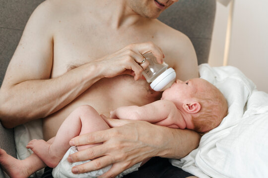 Father bottle-feeding baby and bonding at home