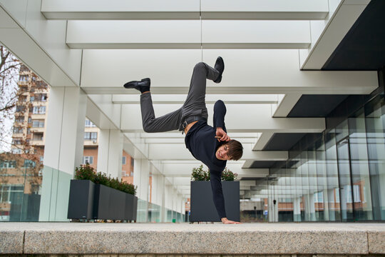 Breakdancer performing energetic move outdoors with modern architecture
