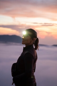 Person with headlamp smiling at foggy mountain summit at sunrise