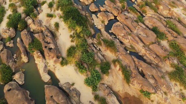 Drone shot of rocky formations and sandbars along the Mekong River in Champassak, Laos, with patches of green vegetation and clear blue water visible.