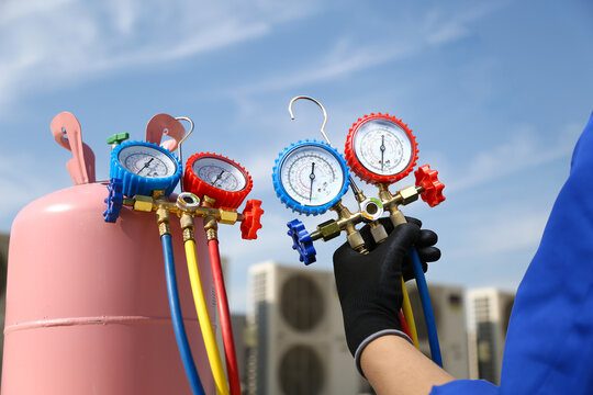 Air conditioning electrical technician service using measuring manifold gauge checking HVAC condition system and refrigerant filling air conditioner after cleaning and maintenance compressor units.