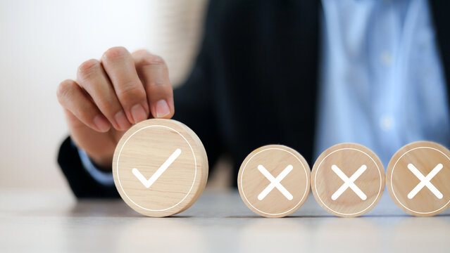 Hand choose check mark with cross symbol on wooden toy stack for true or false changing mindset or way of adapting to change leader and transform quiz answer and poll concept.