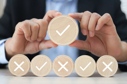Hand choose check mark with cross symbol on wooden toy stack for true or false changing mindset or way of adapting to change leader and transform quiz answer and poll concept.