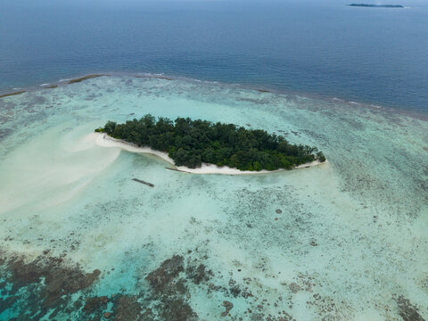 Aerial view of the serene Cemara Kecil Island, where turquoise waters meet the lush greenery, creating a tranquil paradise, Karimunjawa, Central Java, Indonesia.