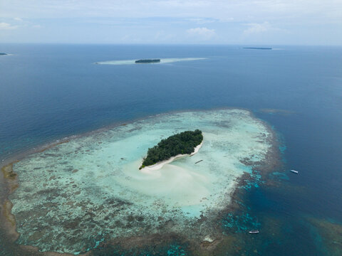 Aerial view of the small island with its lush green interior and surrounding turquoise waters, Cemara Kecil, Central Java, Indonesia.