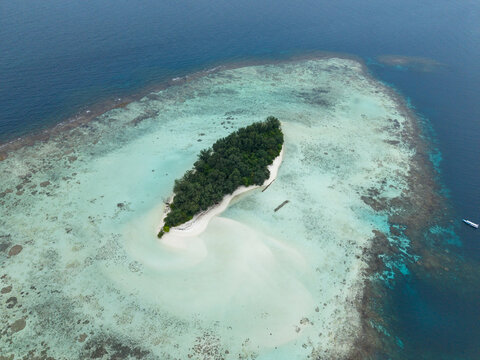 Aerial view of the island's vibrant blues and greens contrast with the sandy shores and lush vegetation, Cemara Kecil Island, Karimunjawa, Central Java, Indonesia.