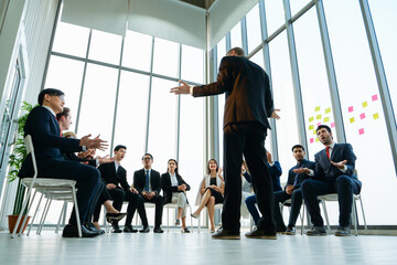 Corporate leadership seminar with male speaker presenting ideas to multicultural professionals in...