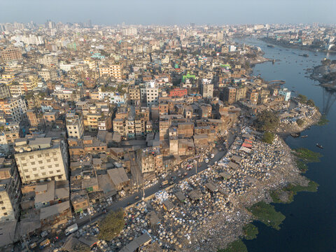 Aerial view of plastic waste densely packed along the Buriganga River's edge contrasts starkly with the city's skyline, Dhaka, Dhaka Division, Bangladesh.