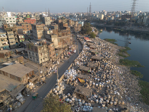 Aerial view of mountains of plastic waste contrasting with the urban landscape, lining the Buriganga River, Dhaka, Dhaka Division, Bangladesh.