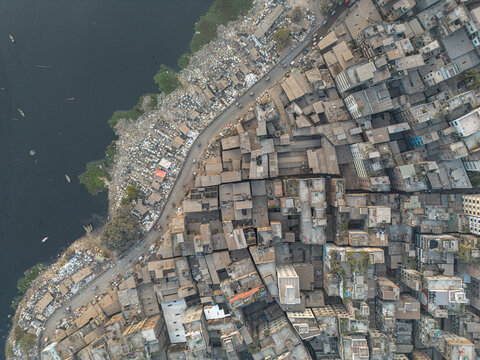 Aerial view of the riverbank crammed with tightly packed buildings and informal settlements reflecting a somber urban tapestry, Dhaka, Dhaka Division, Bangladesh.