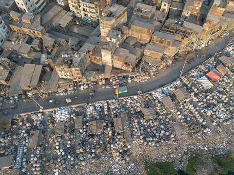 Aerial view of plastic waste sprawling along the Buriganga River's edge contrasting with the adjacent buildings, Dhaka, Dhaka Division, Bangladesh.