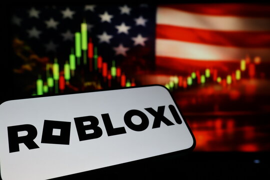 Kiel, Germany - 03-03-2026: US online gaming platform Roblox Corporation logo on smartphone against US flag and rising stock market candlestick chart concept