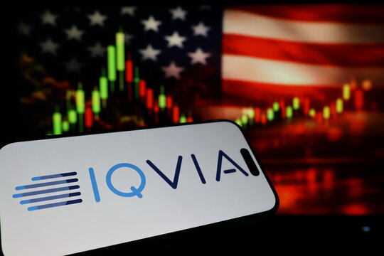 Kiel, Germany - 03-03-2026: US healthcare data analytics company IQVIA Holdings Inc. logo on smartphone against US flag and rising stock market candlestick chart concept