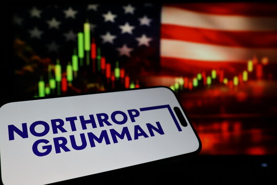 Kiel, Germany - 03-03-2026: US aerospace and defense company Northrop Grumman Corporation logo on smartphone against US flag and rising stock market candlestick chart concept