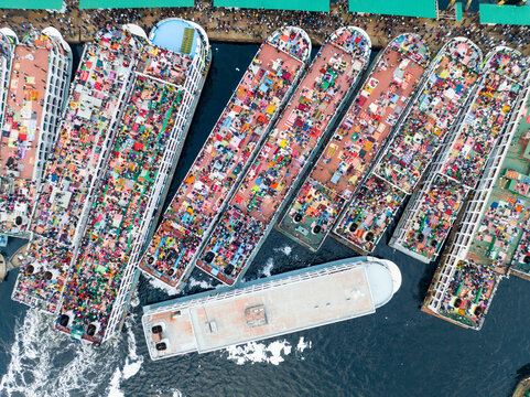 Aerial view of crowded ferries, a vibrant tableau of humanity against the dark waters, bustling at the Sadarghat Boat Terminal, Dhaka, Dhaka Division, Bangladesh.
