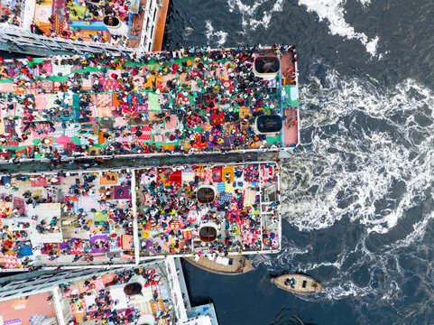 Aerial view of ferries packed with people creating a vibrant mosaic of colors against the dark water, Dhaka, Dhaka Division, Bangladesh.