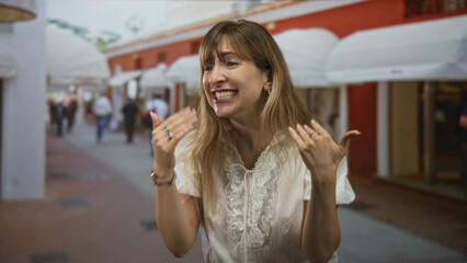 Fototapeta premium Woman shouting with hands raised on a busy pedestrian street, palm forward gesture and strained facial expression; anger frustration.
