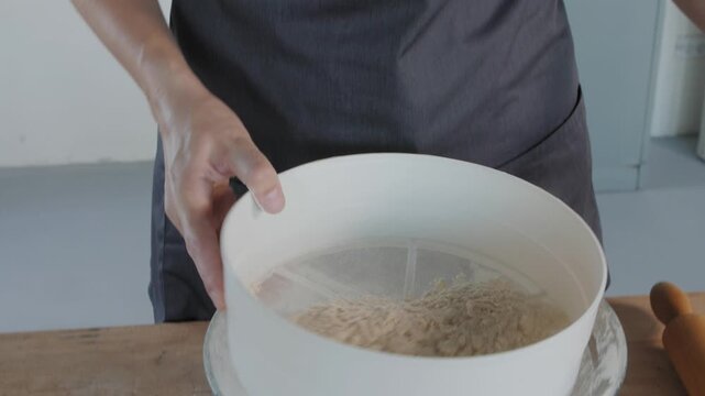 Professional baker sifting flour for baking dough