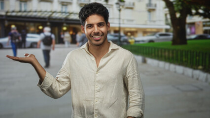 Man presenting with palm up on a street in a beige linen shirt, face turned to camera, open hand...