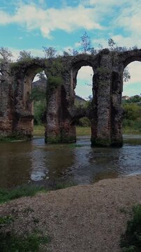 Vertical drone pullback revealing the ancient arches of the Roman Aqueduct of Nicopolis in Epirus Greece, featuring the scenic Louros river and historic masonry for social media travel content.