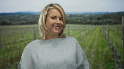 Fototapeta premium Young blonde woman blows a kiss with her lips toward the camera in a green forest setting; affection.
