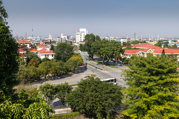 Obraz premium High-angle view of a vibrant Hoa Lu Old town, , Ninh Binh, Vietnam, capturing daily urban life with cars, buses, and buildings amidst green trees.