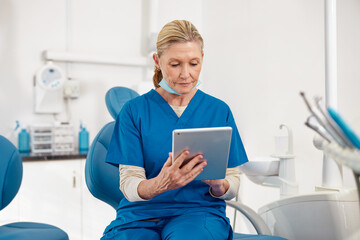 Mature woman dentist using digital tablet