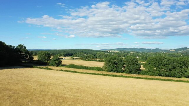 Scenic view of rolling fields and green trees under a blue sky in the Morvan countryside, France. Peaceful rural landscape with distant hills and scattered clouds.