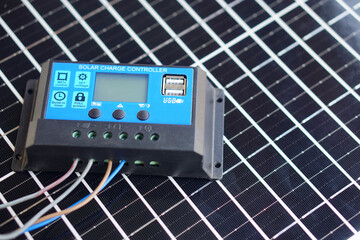 Solar charge controller with USB port connected by wires placed on photovoltaic solar panel. Renewable energy management device for battery charging and off grid power systems. © Sanhanat