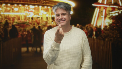 Fototapeta premium Man points finger at camera on crowded street with carousel lights and evening fair atmosphere; mischievous invitation.