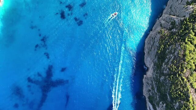 Aerial drone view of famous Navagio Shipwreck Beach with turquoise sea water and boats in Zakynthos island, Greece on a bright sunny da