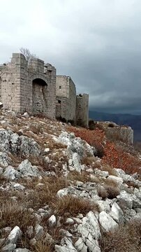 Golo Brdo fortress tower against dark pre-storm sky in Trebinje. Represents imperial defense architecture, tension-filled historic setting, abandoned military monument, and dramatic European backdrop.